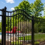 Residential black metal pool safety fence and arched entry gate installed in a Southern Wisconsin residential backyard.